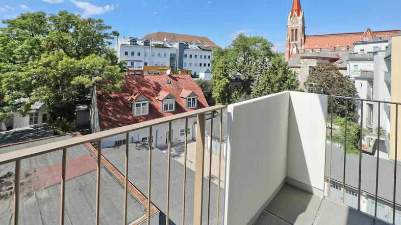 Balkon mit Blick auf die umliegenden Gebäude und eine Kirche unter blauem Himmel.