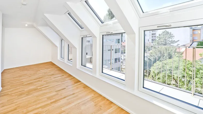 Helles Wohnzimmer im Dachgeschoss mit Parkettboden, Dachfenstern und französischem Balkon.
