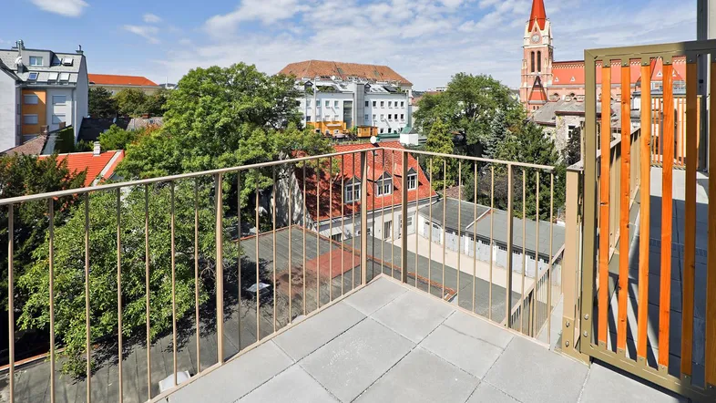 Geräumige Dachterrasse mit Fliesenboden und weitem Blick über die Stadt und einen Kirchturm.