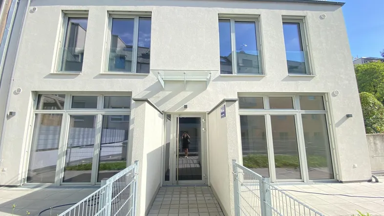 Moderne Gebäudefassade mit großen Fenstern und einem barrierefreien Eingangsbereich.