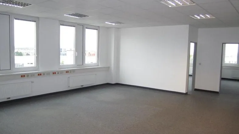 Geräumiges Büro mit großen Fenstern, Teppichboden und abgehängter Decke, bereit zur Nutzung.