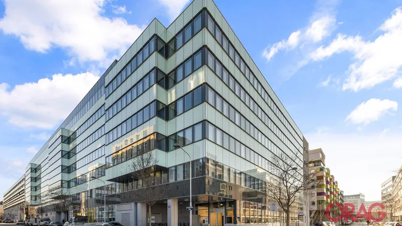 Modernes Bürogebäude mit Glasfassade und vielen Fenstern unter blauem Himmel.