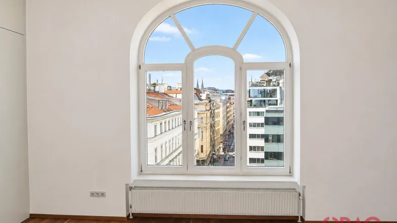 Heller Raum mit großem Rundbogenfenster bietet einen weiten Blick über die belebte Stadtstraße.