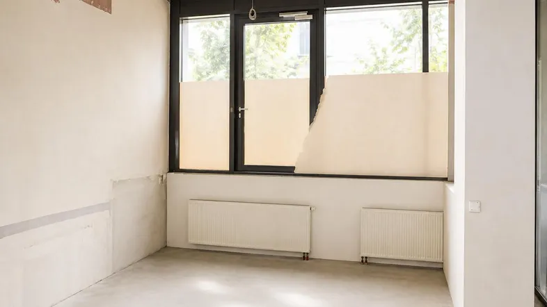 Unfertiger Raum mit großen Fenstern und Heizkörpern, bereit für den Innenausbau.