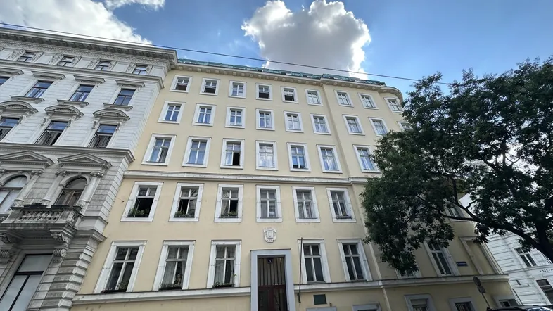 Klassisches Mehrfamilienhaus mit vielen Fenstern und traditioneller Architektur in städtischer Umgebung.