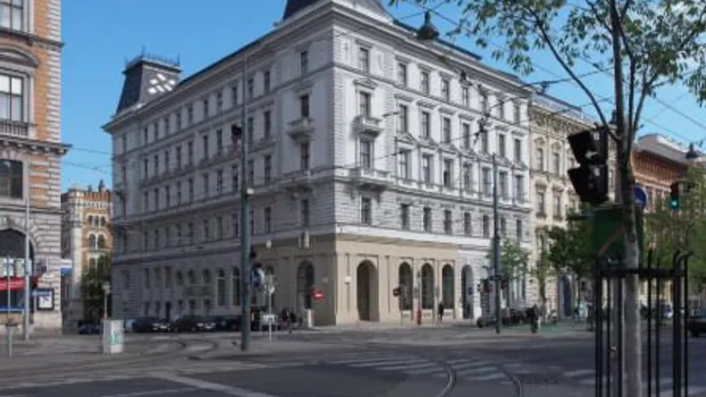 Elegantes Eckgebäude mit klassischer Architektur und Mansarddach an einer städtischen Kreuzung.
