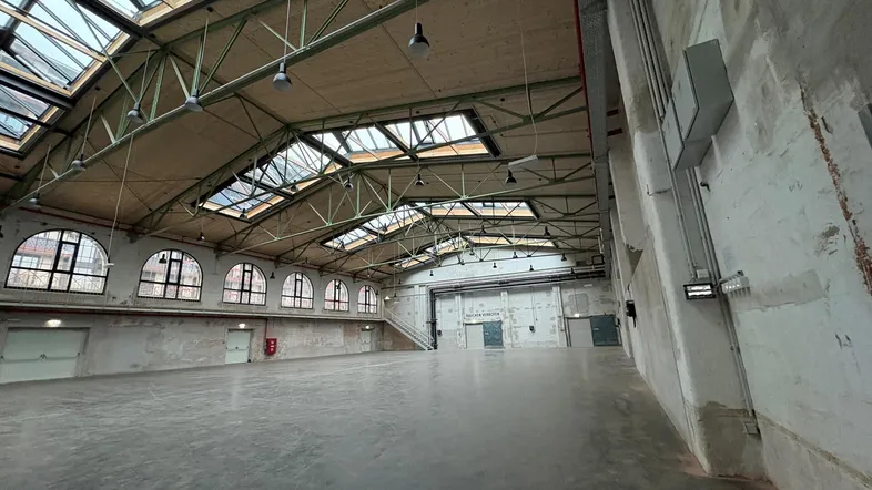 Große, leere Halle mit hohen Decken, Oberlichtern und sichtbaren Dachkonstruktionen, ideal für Veranstaltungen oder Lager.