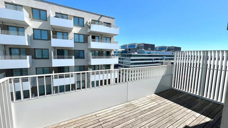 Geräumige Terrasse mit Holzboden und Blick auf moderne Wohngebäude in der Stadt.