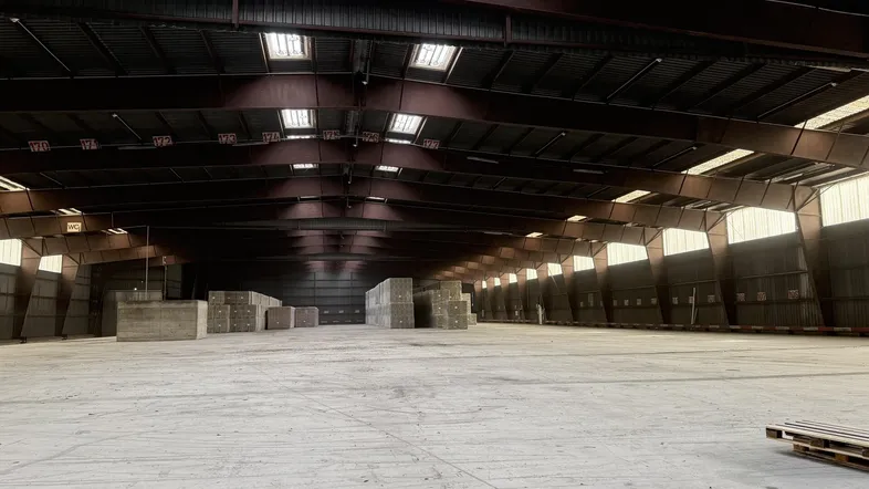 Große, leere Lagerhalle mit hohen Decken, Oberlichtern und Betonboden, bereit zur Nutzung.