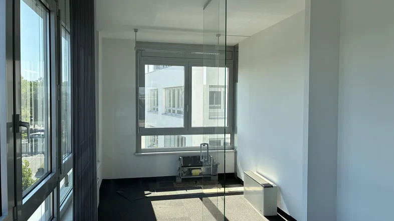 Helles Büro mit großen Fenstern, Teppichboden und modernen Glaswänden für eine offene Arbeitsumgebung.