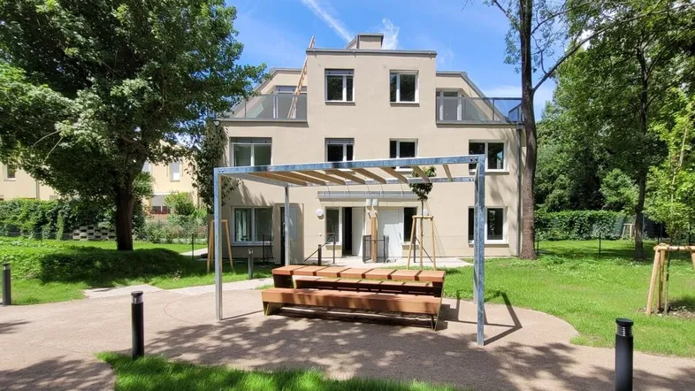 Moderne Wohnanlage mit gemeinschaftlichem Außenbereich, Pergola und Spielplatz.