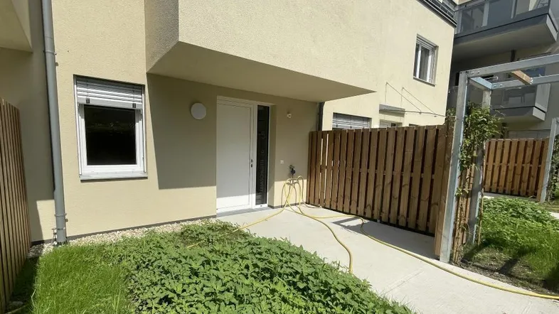 Eingangsbereich eines modernen Reihenhauses mit kleiner Grünfläche und Holzzaun.
