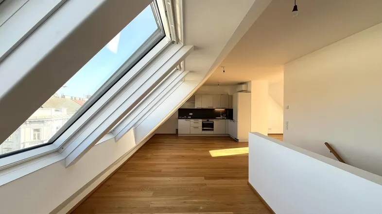 Heller, offener Wohnbereich mit Dachfenstern, Holzboden und integrierter moderner Küche.