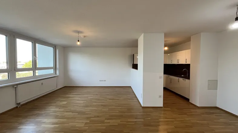 Heller Wohnbereich mit Parkettboden und offener Küche, ideal für einen modernen Lebensstil.