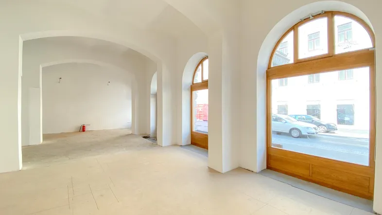 Großer, heller Gewerberaum mit hohen Gewölbedecken und großen Rundbogenfenstern zur Straße.