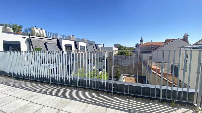 Geräumige Dachterrasse mit modernem Metallgeländer und Blick über die umliegenden Gebäude.
