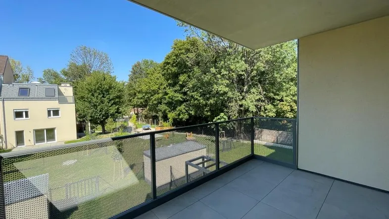 Geräumiger Balkon mit modernem Glasgeländer und Blick ins Grüne, ideal zum Entspannen im Freien.
