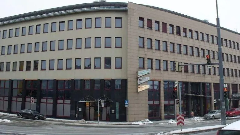 Mehrstöckiges Bürogebäude an einer Straßenecke mit vielen Fenstern und moderner Architektur.
