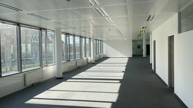 Großes, leeres Büro mit vielen Fenstern, die viel Tageslicht hereinlassen und einen weiten Blick bieten.