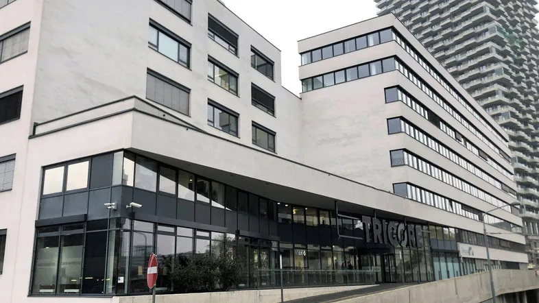 Modernes Geschäftsgebäude mit heller Fassade und großen Glasflächen, inklusive einer Zufahrtsrampe.