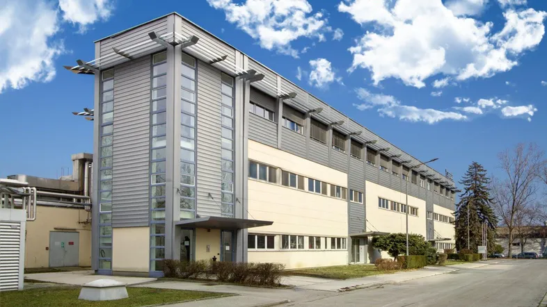 Modernes Büro- oder Industriegebäude mit großen Fenstern und einer strukturierten Fassade unter blauem Himmel.