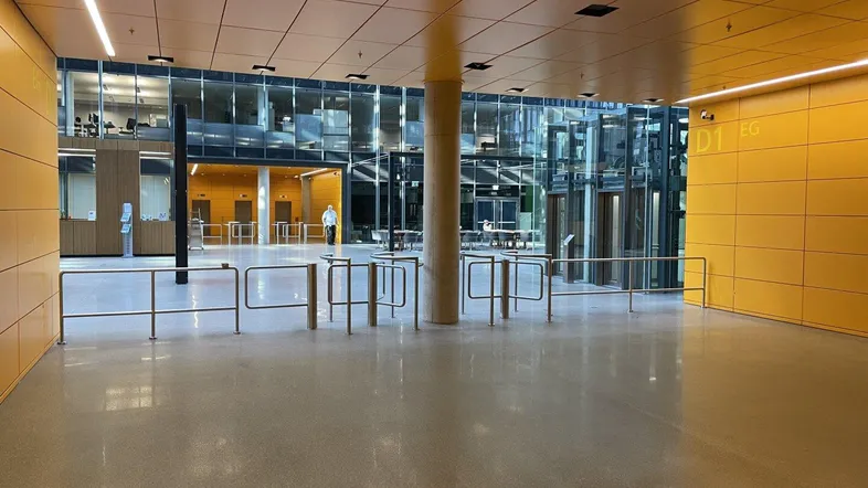 Geräumige und moderne Lobby mit gelben Akzentwänden, Glasfassaden und Zugangskontrolle.