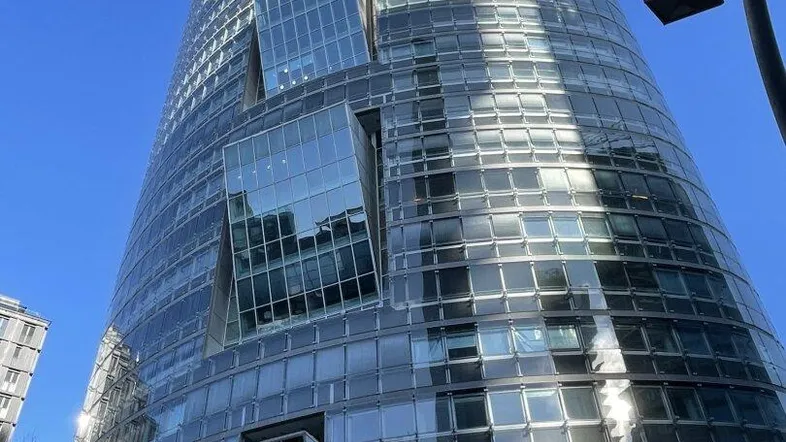Beeindruckendes modernes Hochhaus mit gläserner Fassade und markanter Architektur unter blauem Himmel.