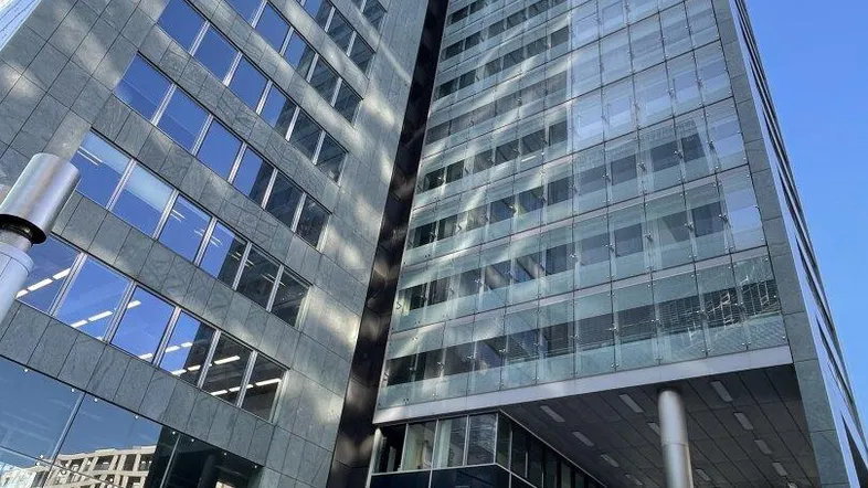 Modernes Hochhaus mit beeindruckender Glasfassade und klarem blauen Himmel, das eine städtische Umgebung prägt.