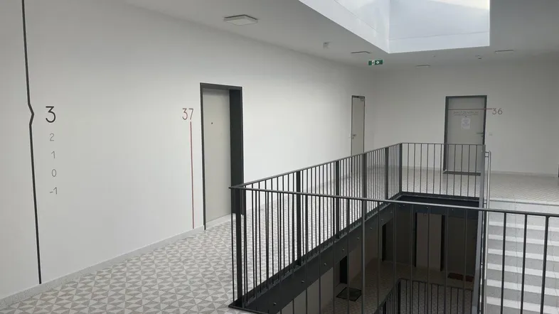 Heller Treppenhausbereich mit Oberlicht, modernen Geländern und gemustertem Bodenbelag in einem Neubau.