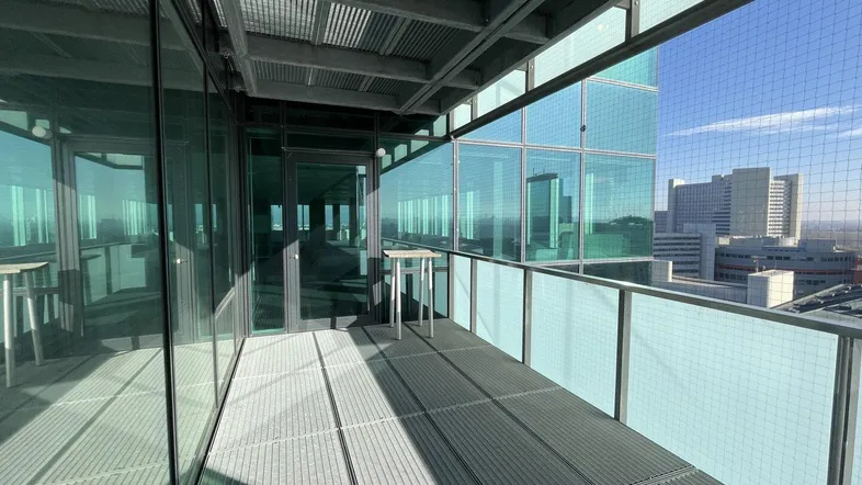 Geräumiger Balkon mit Metallboden und Glasgeländer bietet einen weiten Blick über die Stadtlandschaft.