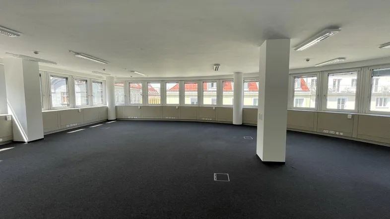 Helles und geräumiges Büro mit Teppichboden und einer Reihe von Fenstern, die den Raum erhellen und eine angenehme Atmosphäre bieten.
