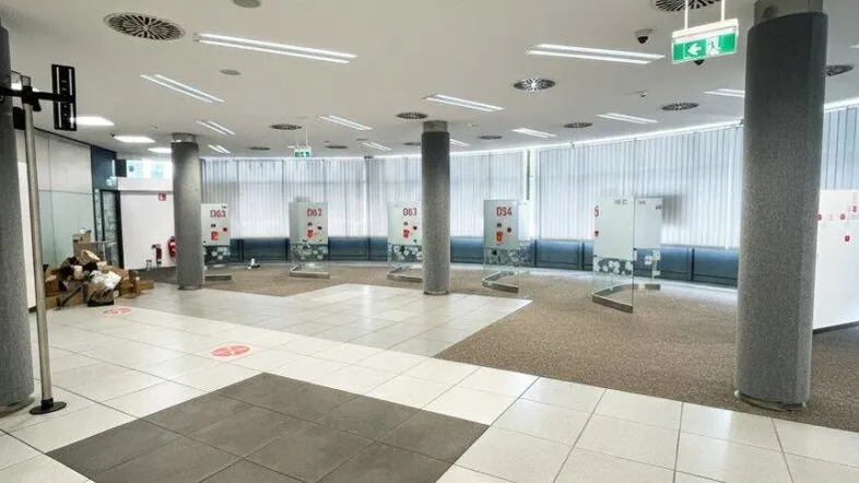 Geräumiger, moderner Bürobereich mit Fliesen- und Teppichboden, hohen Decken und viel natürlichem Licht.