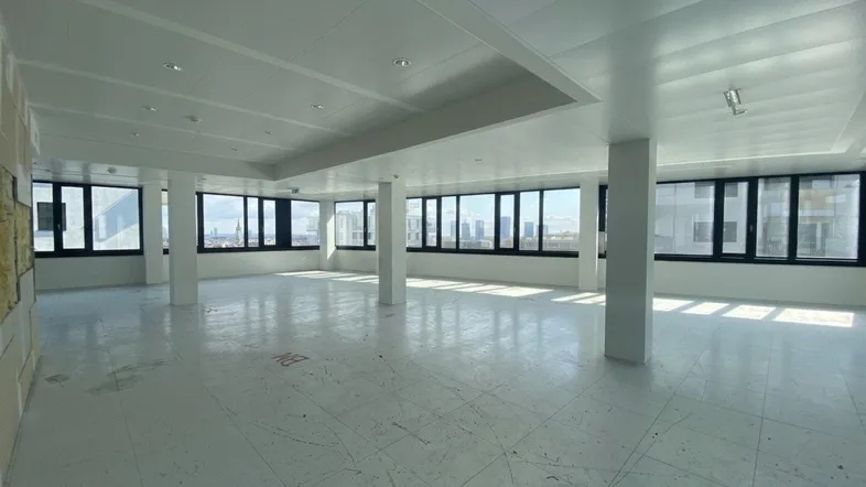 Geräumiges, leeres Büro mit vielen Fenstern, die einen weiten Blick auf die Stadt bieten.