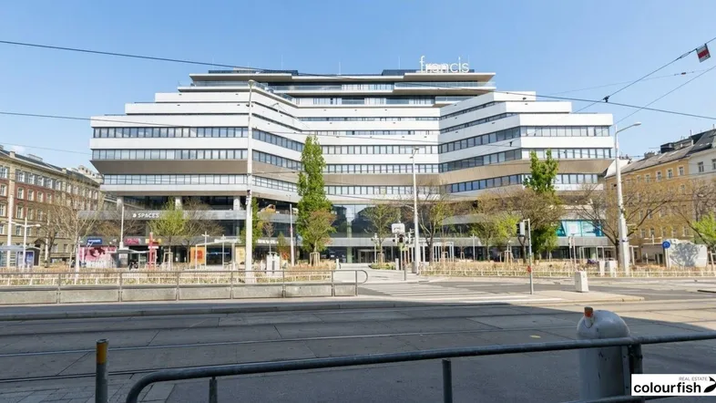 Modernes Bürogebäude mit gestufter Architektur und großen Fensterfronten an einer belebten Straße.