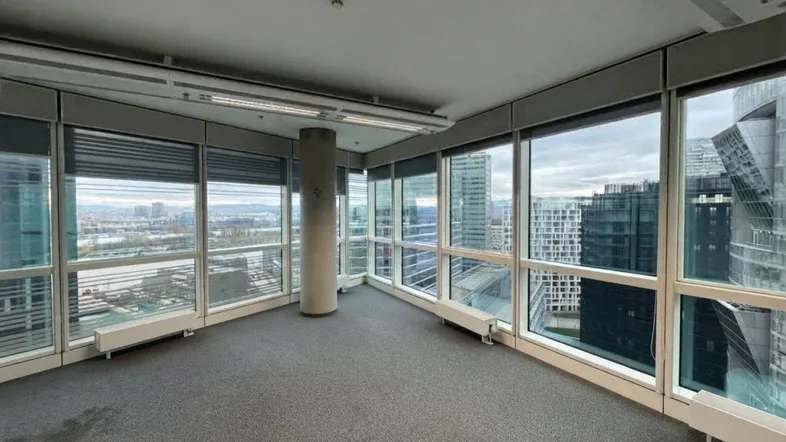 Geräumiges Büro mit Teppichboden und großen Fenstern, die einen weiten Blick auf die Stadt bieten.