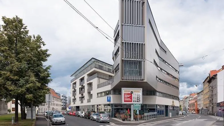 Modernes Gebäude an einer Straßenecke mit Geschäften im Erdgeschoss und Wohnungen darüber.
