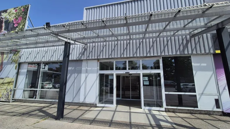 Die moderne Fassade des Geschäftsgebäudes mit großen Glasfronten und einem schützenden Vordach über dem Eingangsbereich.