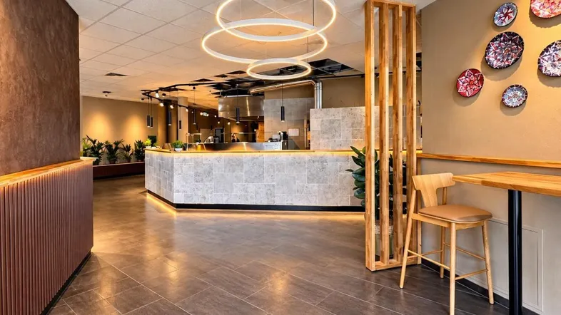 Moderner Restaurantbereich mit stilvoller Theke, ringförmigen Deckenleuchten und dekorativen Wandtellern.