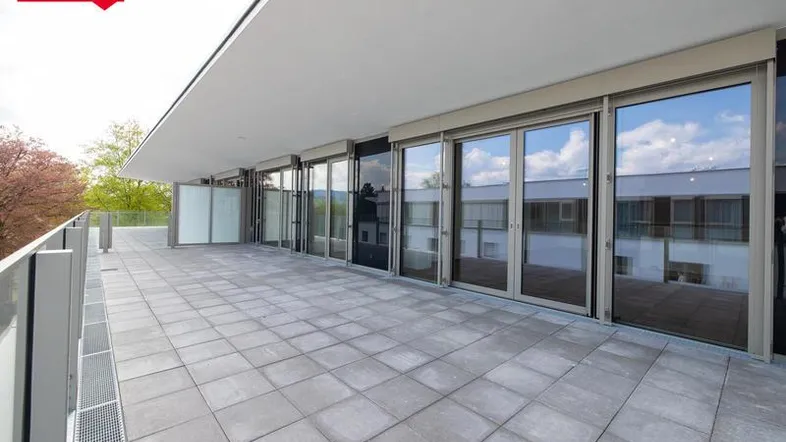 Weitläufige Dachterrasse mit modernen Fliesen und raumhohen Fenstern, die viel Licht hereinlassen.