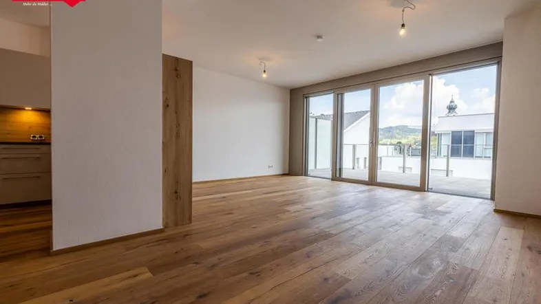 Helles Wohnzimmer mit Holzboden und großen Schiebetüren zur Terrasse mit Bergblick.