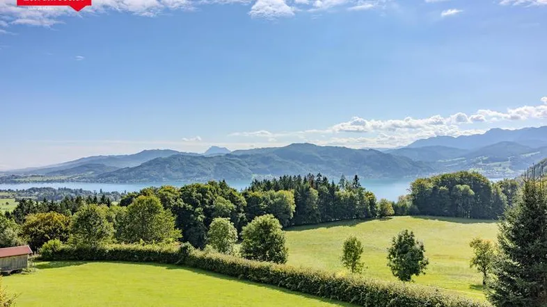 Malerischer Ausblick auf den See, die umliegende Landschaft und die fernen Berge.