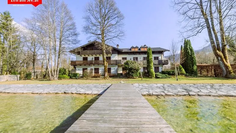 Traditionelles Haus am Seeufer mit mehreren Balkonen und großem Gartenbereich.