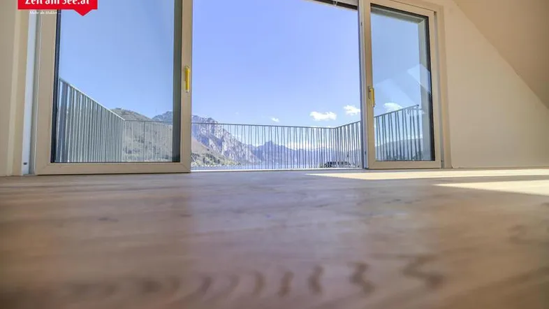 Heller Wohnraum mit Schiebetüren, die einen atemberaubenden Blick auf die Berge und den See freigeben.