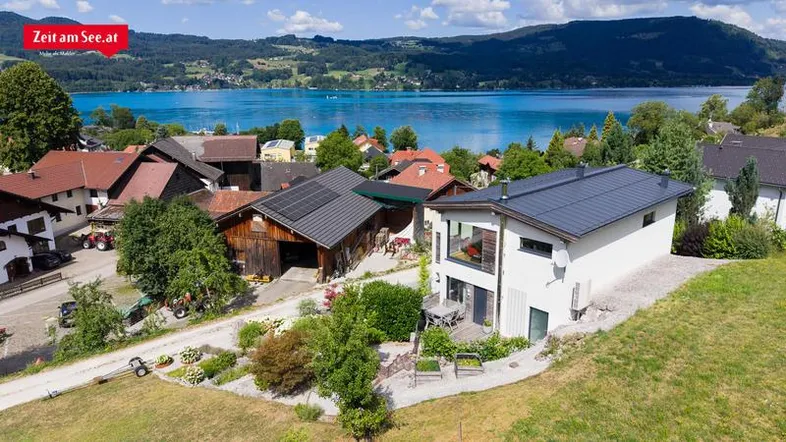 Luftaufnahme des modernen Hauses mit Solarpaneelen und malerischer Lage am Seeufer.