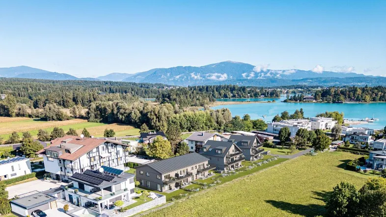 Luftaufnahme einer modernen Wohnanlage mit Blick auf den See und die umliegende Berglandschaft.