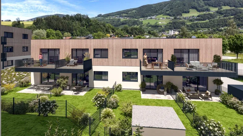 Moderne Reihenhäuser mit Holzfassaden, privaten Gärten und Balkonen in grüner Umgebung mit Bergblick.