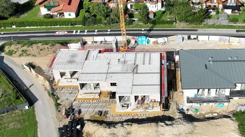 Luftaufnahme einer Baustelle mit einem im Bau befindlichen Gebäude und einem Kran in ländlicher Umgebung.