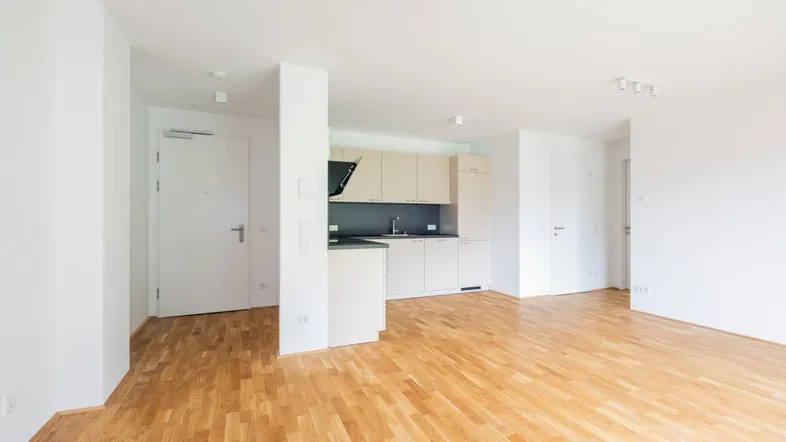 Heller offener Wohnbereich mit integrierter Küche und warmem Holzfußboden, ideal für modernes Wohnen.