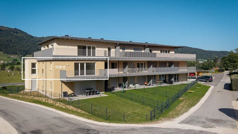 Modernes Mehrfamilienhaus mit mehreren Balkonen und Terrassen in ländlicher Umgebung.