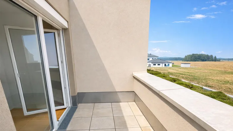 Geräumiger Balkon mit Fliesenboden und weitem Blick über Felder und die Landschaft.